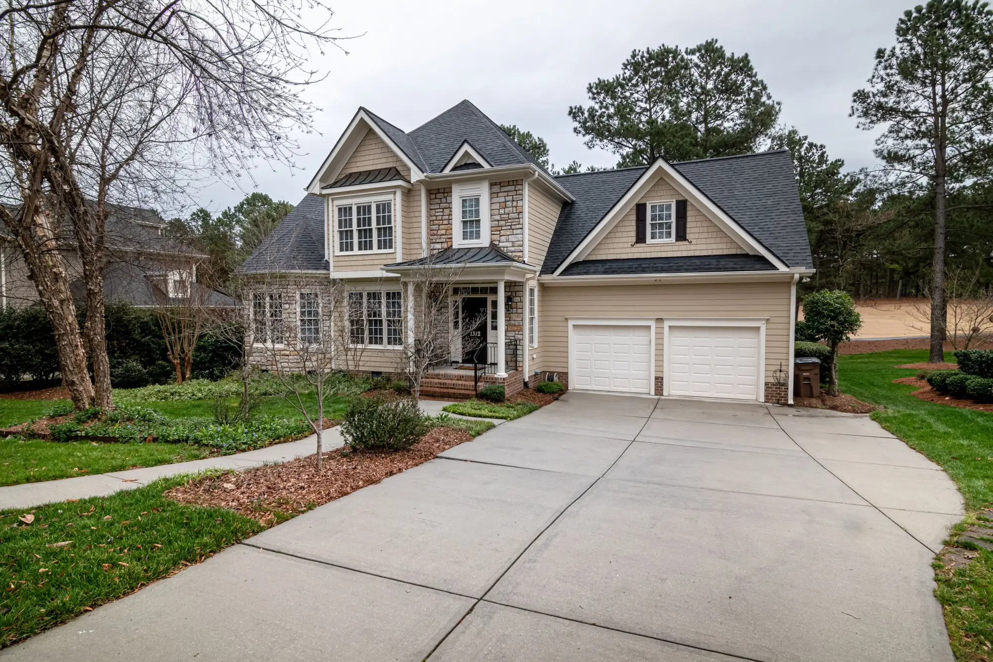 A two-storey house with a two-car garage and a wide concrete driveway